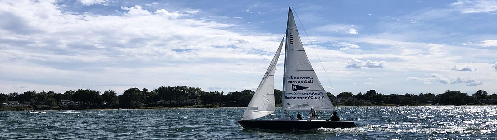 Adults sailing small sailboats on open water