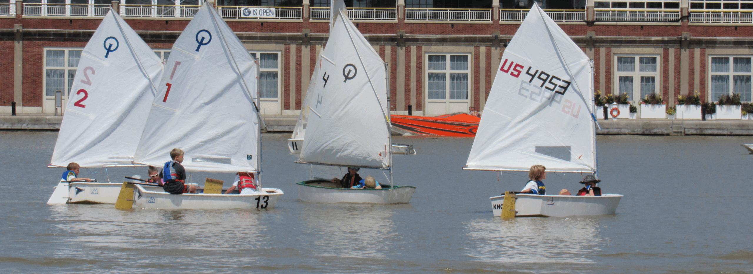 Group of junior sailors on small sailboats participating in a sailing program