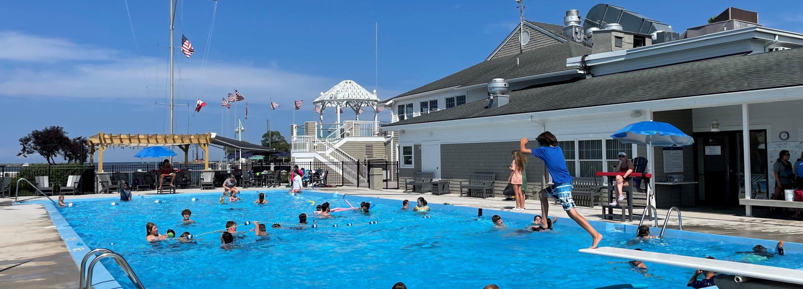 Outdoor swimming pool area with lounge chairs and umbrellas beside a body of water
