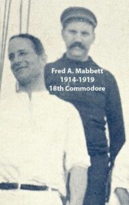 Black‑and‑white portrait of a yacht club commodore wearing a formal jacket and commodore’s cap