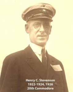 Black‑and‑white portrait of a yacht club commodore wearing a suit and cap