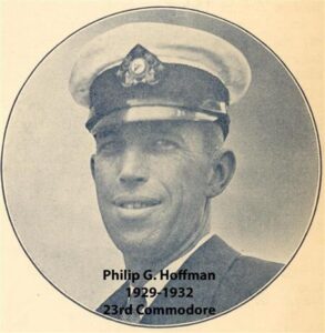 Black‑and‑white portrait of a yacht club commodore wearing a suit and cap
