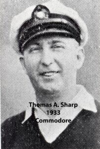 Black‑and‑white portrait of a yacht club commodore wearing a suit and cap
