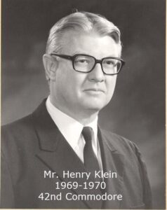 Black and white portrait of a middle‑aged man wearing glasses and a suit
